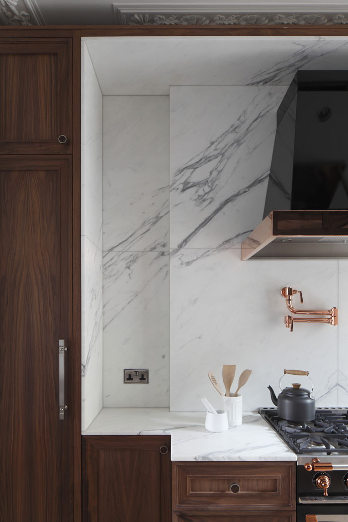 Bespoke kitchen with panelled walnut cabinets, with book matched Statuario marble surround and splash back. Le Cornue oven and extractor hood.