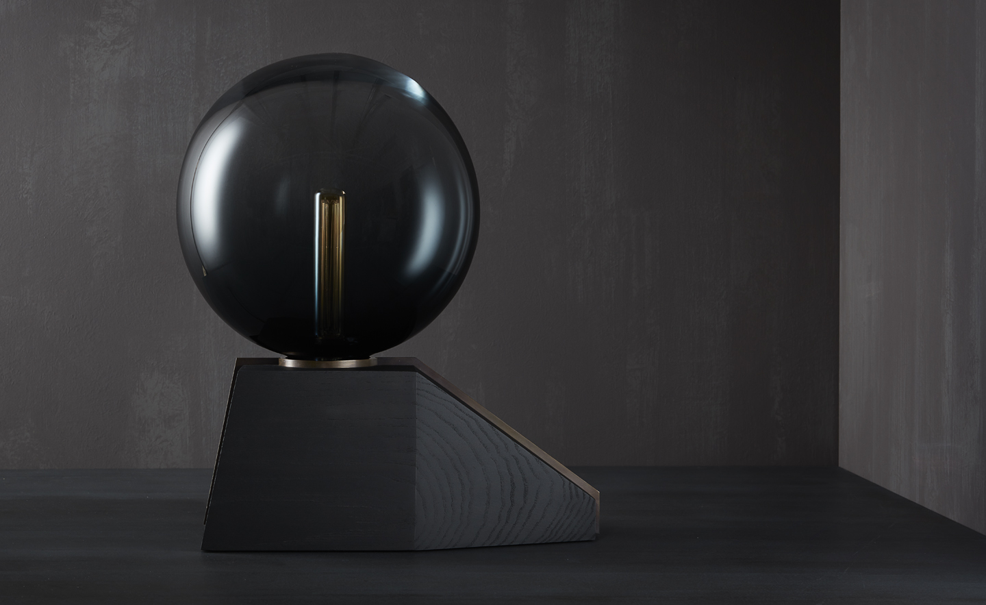 Table lamp designed by Studioloop, with Murano glass globe, blackened ash base and bronze strap detail