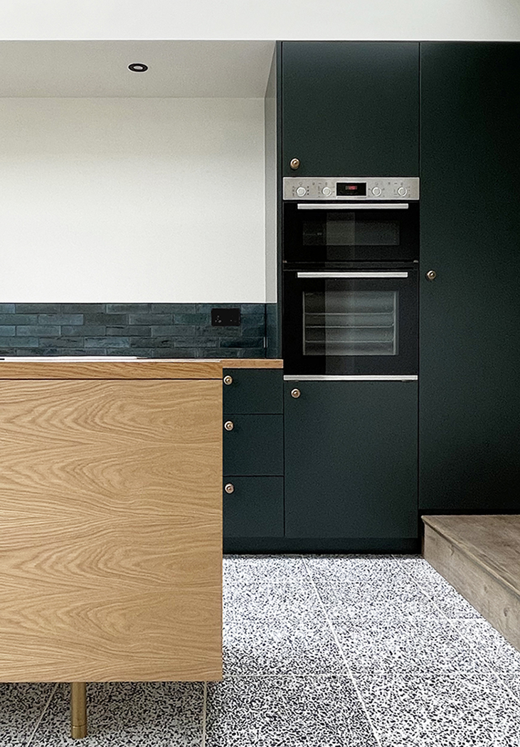 Oak kitchen island, with oak counter tops and deep green cabinets 