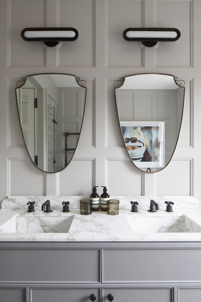 Panelled master bathroom with stone sinks and bespoke cabinetry. Antique mirrors and Apparatus Studio wall lights