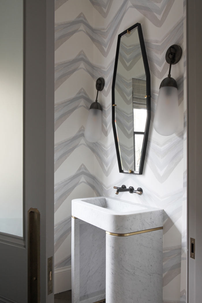 Wallpapered guest bathroom with stone sink from Lapicida and Apparatus Studio wall lights