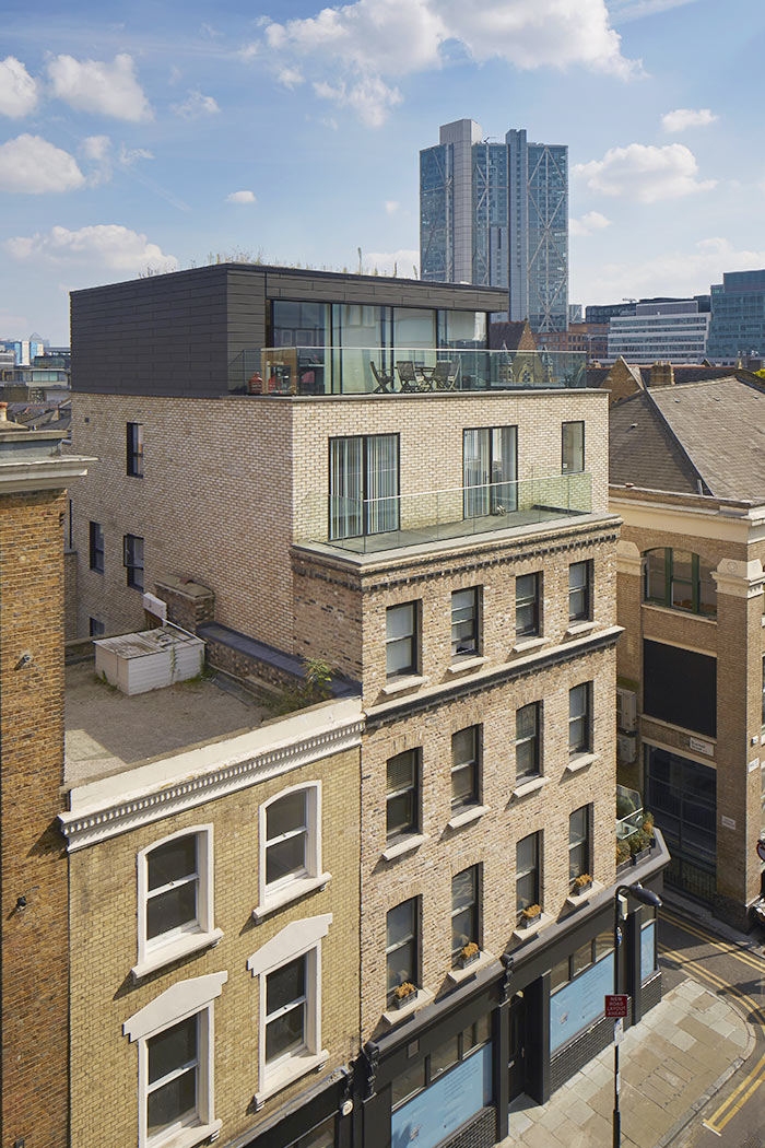 Zinc clad rooftop extension, set back from main brick facade. Glass balustrades and traditional details, with historic shopfront in the Shoreditch Conservation Area.