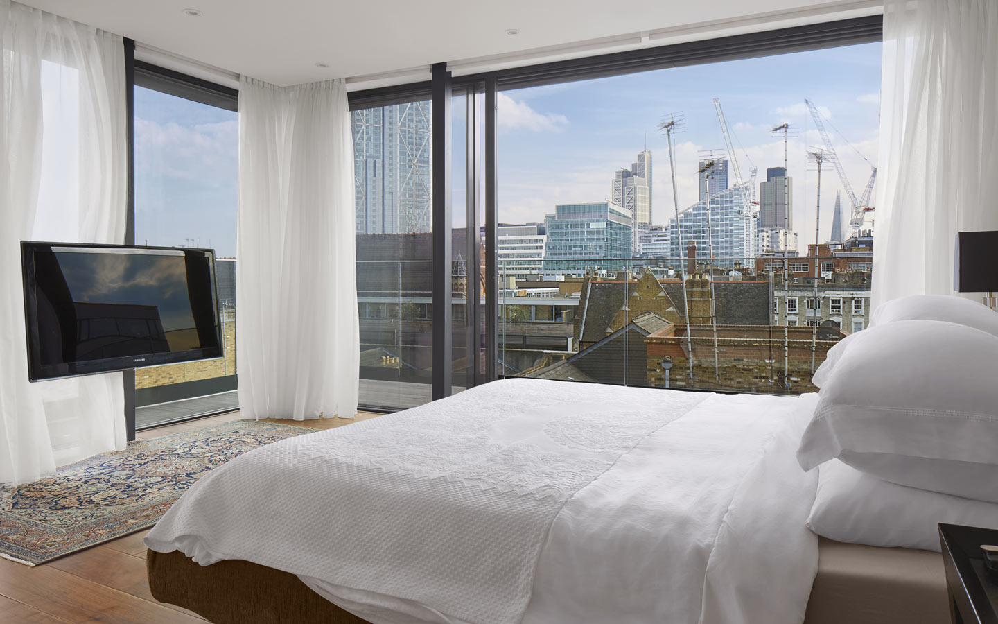 Perimeter glazing to the master bedroom with recessed double curtain tracks, with views to Shoreditch and Bishopsgate.