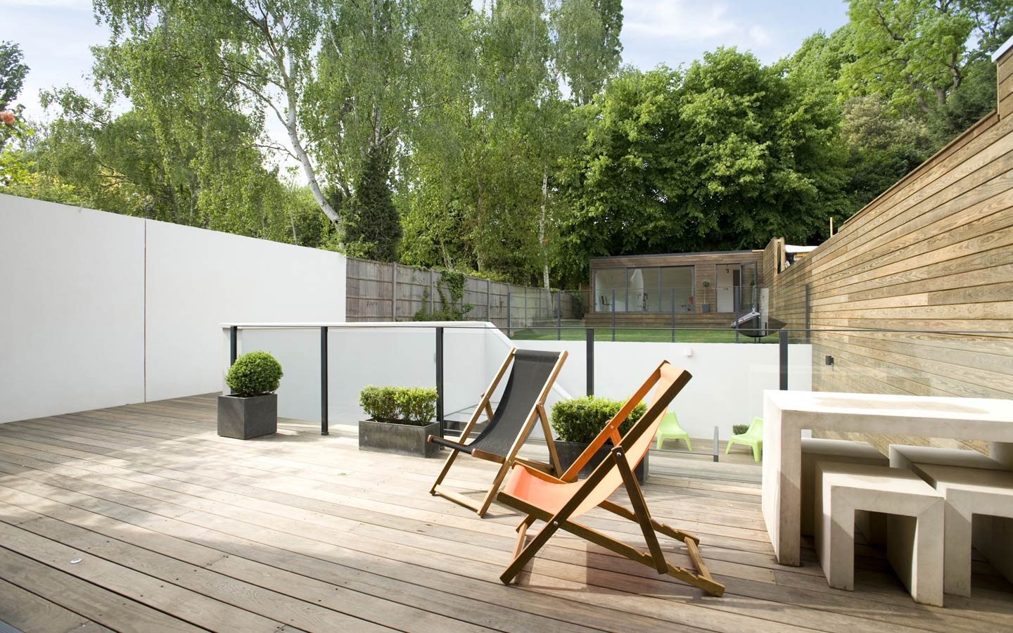 Kebony decking to raised garden level, glass balustrade and rendered walls.