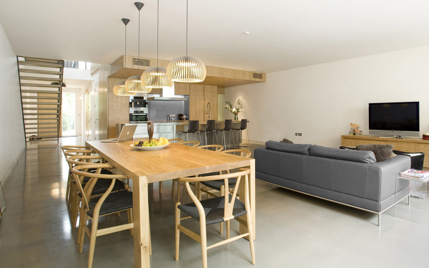 Family room with polished concrete floor, stainless steel island unit, oak kitchen wall units, oak dining table.