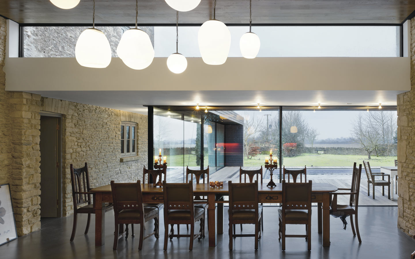 Dining and kitchen with polished concrete floor, original stone walls, floor to ceiling sliding doors out to timber deck and swimming pool.