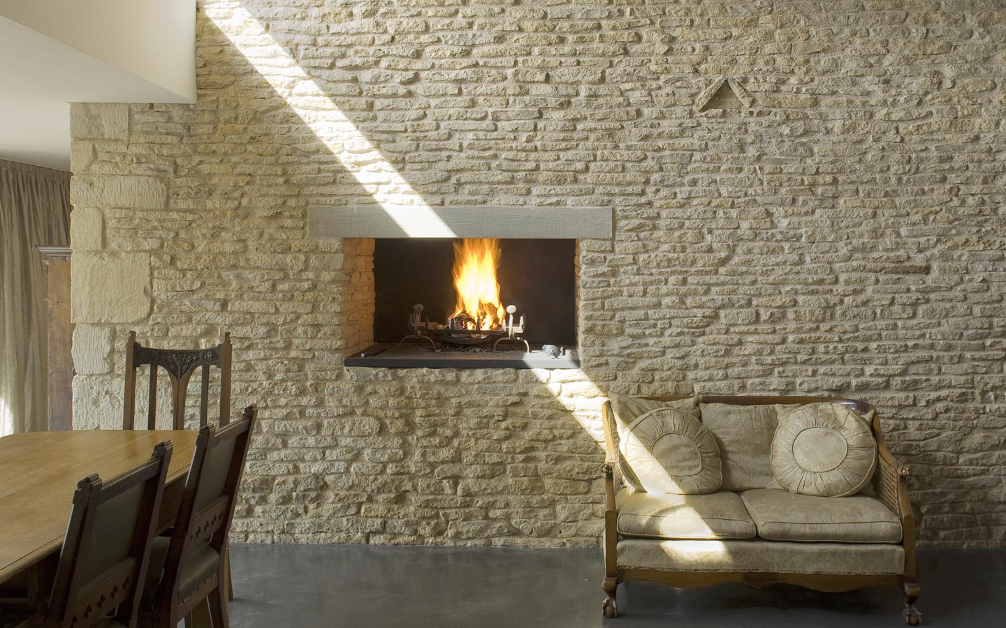 Dining area with recessed fireplace, set with the original stone barn walls and slate hearth.