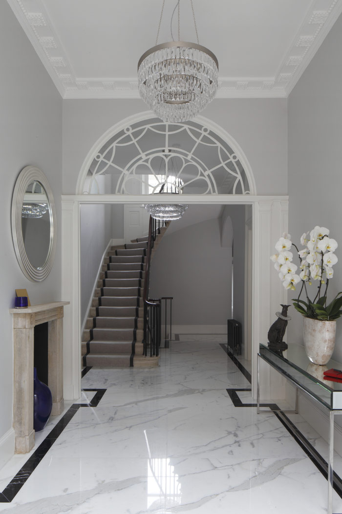 Entrance hall with original Georgian fanlight, stone fireplace and cantilevered stone staircase. New Statuario marble floor with Nero Marquina perimeter detail