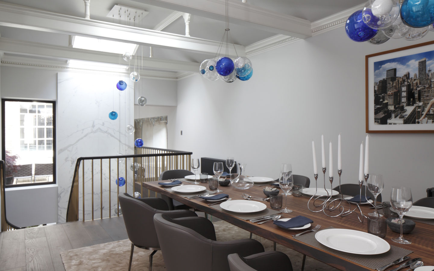 Dining area created within the old stable building to large Georgian house. Double height Statuario marble wall detail with Bocci Chandelier.
