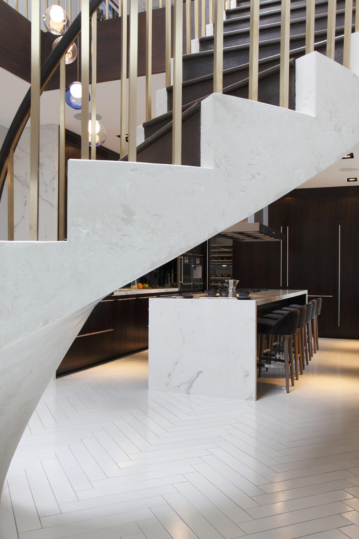 Townhouse lower ground kitchen, with Lavastone herringbone tiled floor, white concrete staircase. Statuario marble counter with stained oak cabinets, Gaggenau fittings throughout