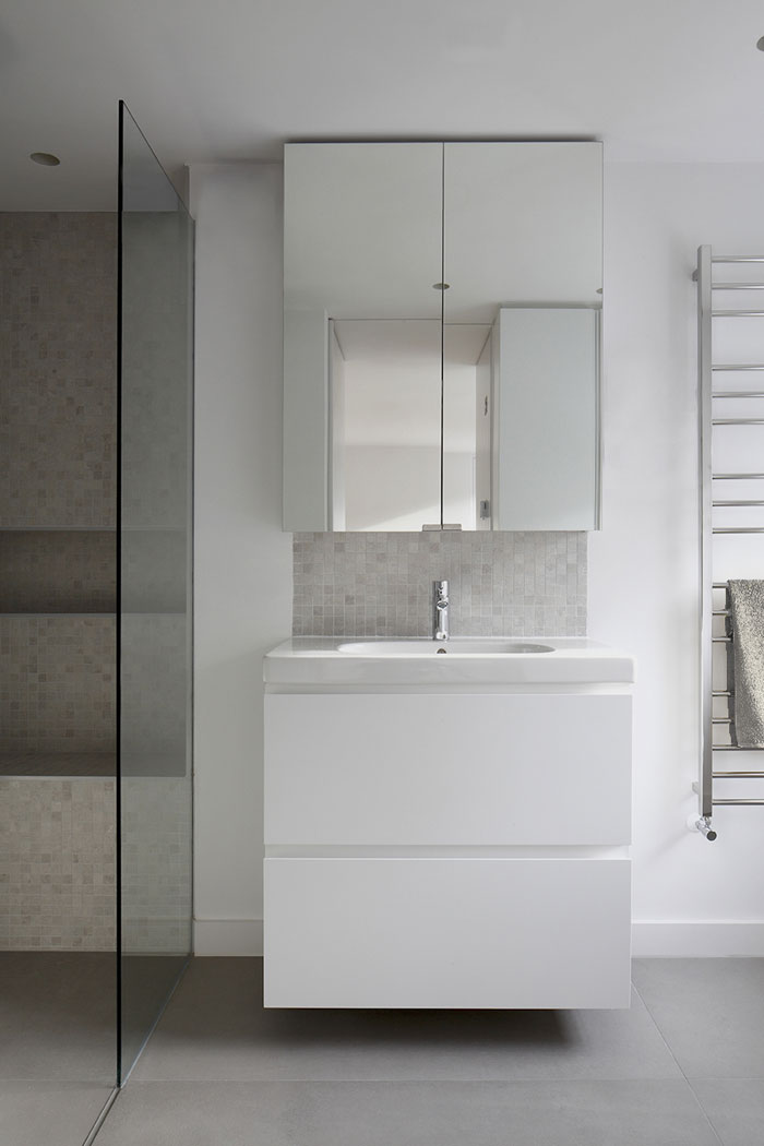 New bathroom, with shower enclosure, mirrored cabinet and under sink unit, concrete tiled floor at this Georgian house refurbishment.