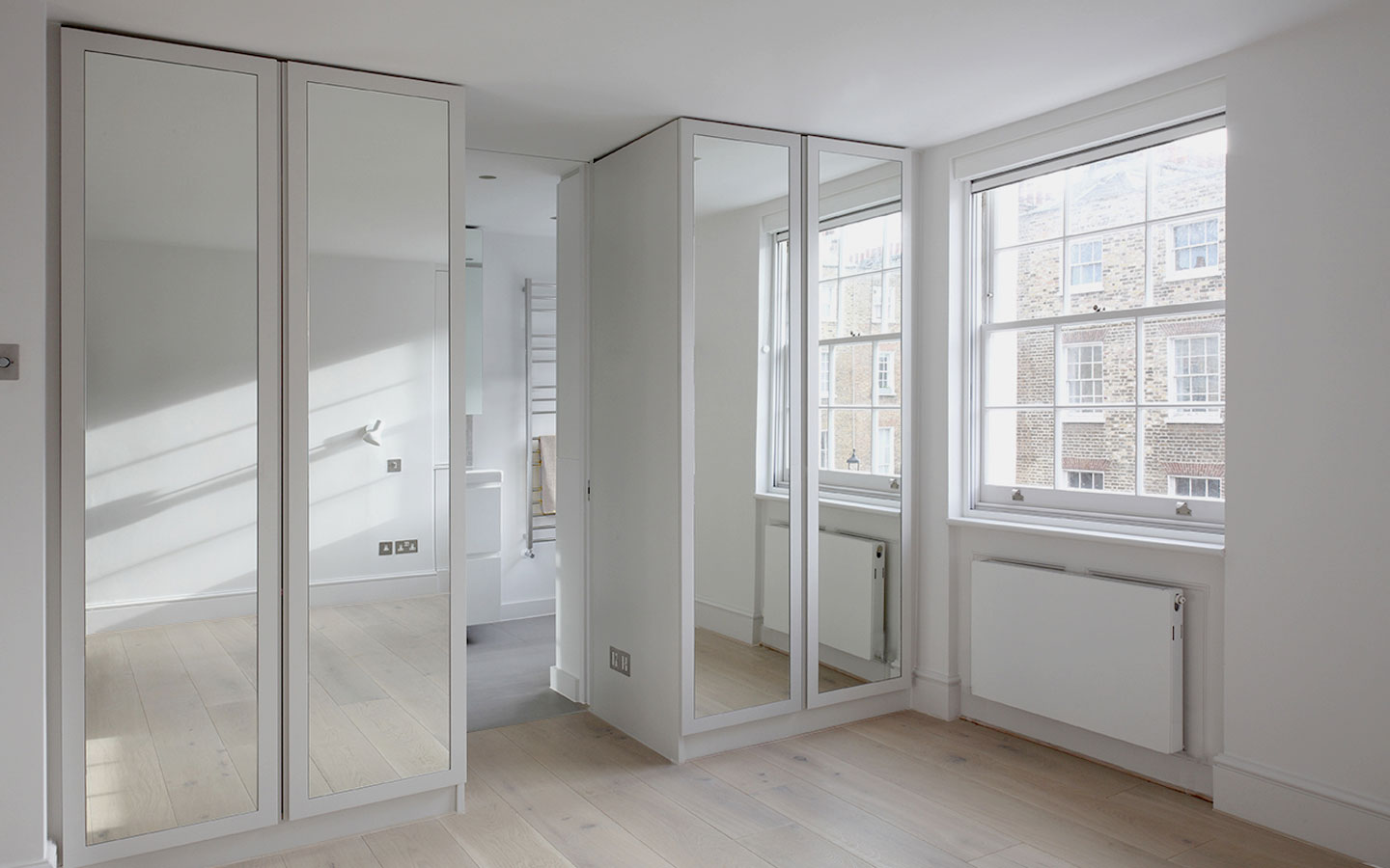 Bespoke mirrored cabinets form entrance to bathroom area at this Georgian House refurbishment.
