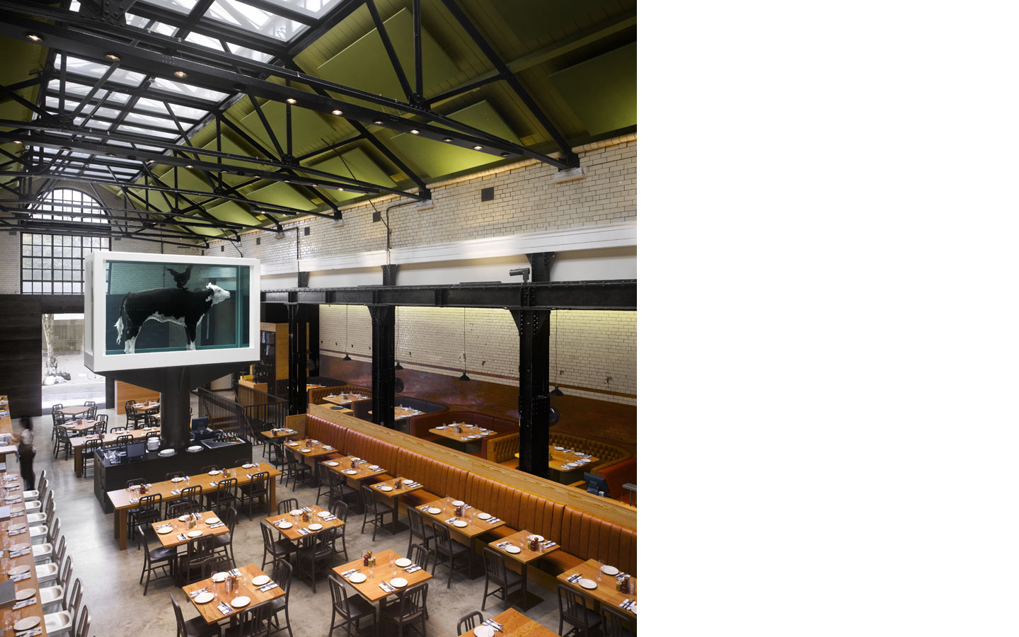 Tramshed Shoreditch, main dining area within the old Tramshed, original ironwork , original glazed tiles and large glazed fanlight. New leather banquette seating and Douglas fir joinery throughout, with Damien Hurst sculpture.