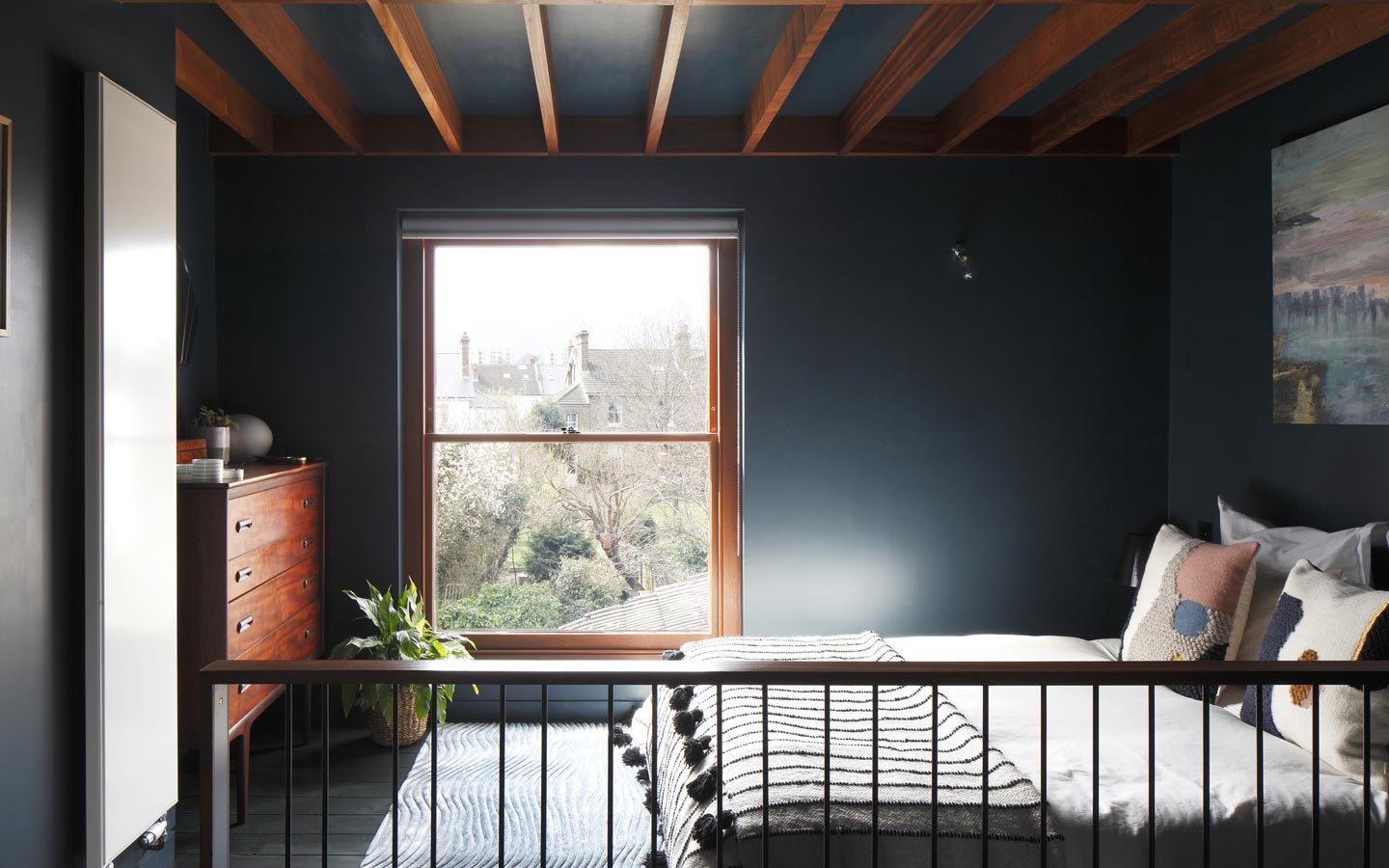 Rooftop extension, bedroom with exposed beams, large timber sash window and Farrow and Ball Hague Blue walls.