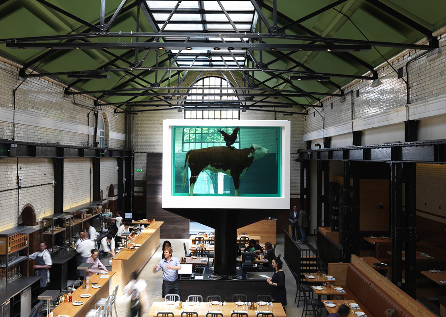 Tramshed Shoreditch main dining area within the old Tramshed, original ironwork and original glazed tiles, with Damien Hurst sculpture positioned centrally.